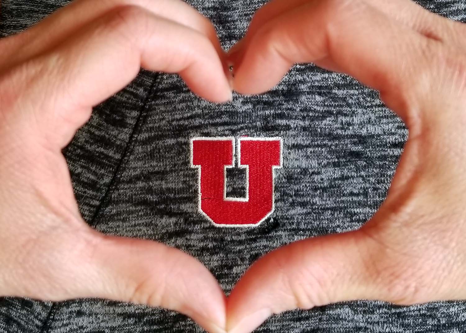 Two hands forming a heart around the block U logo