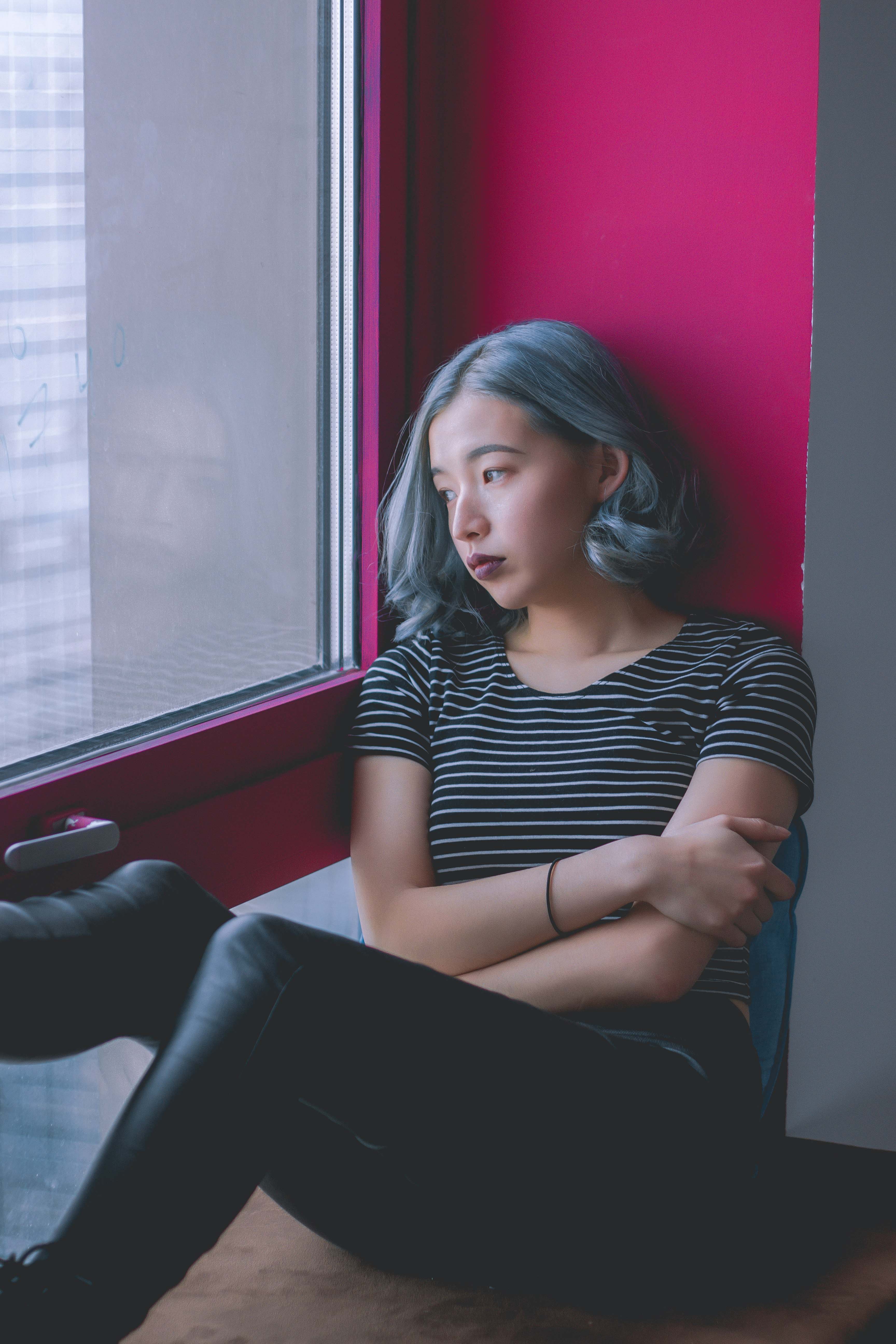 a young woman looks out a window with a thoughtful expression on her face