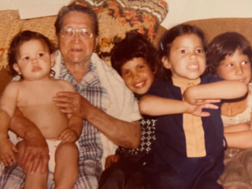 An old photo of an older woman with a little boy on her lap, next to three other childen