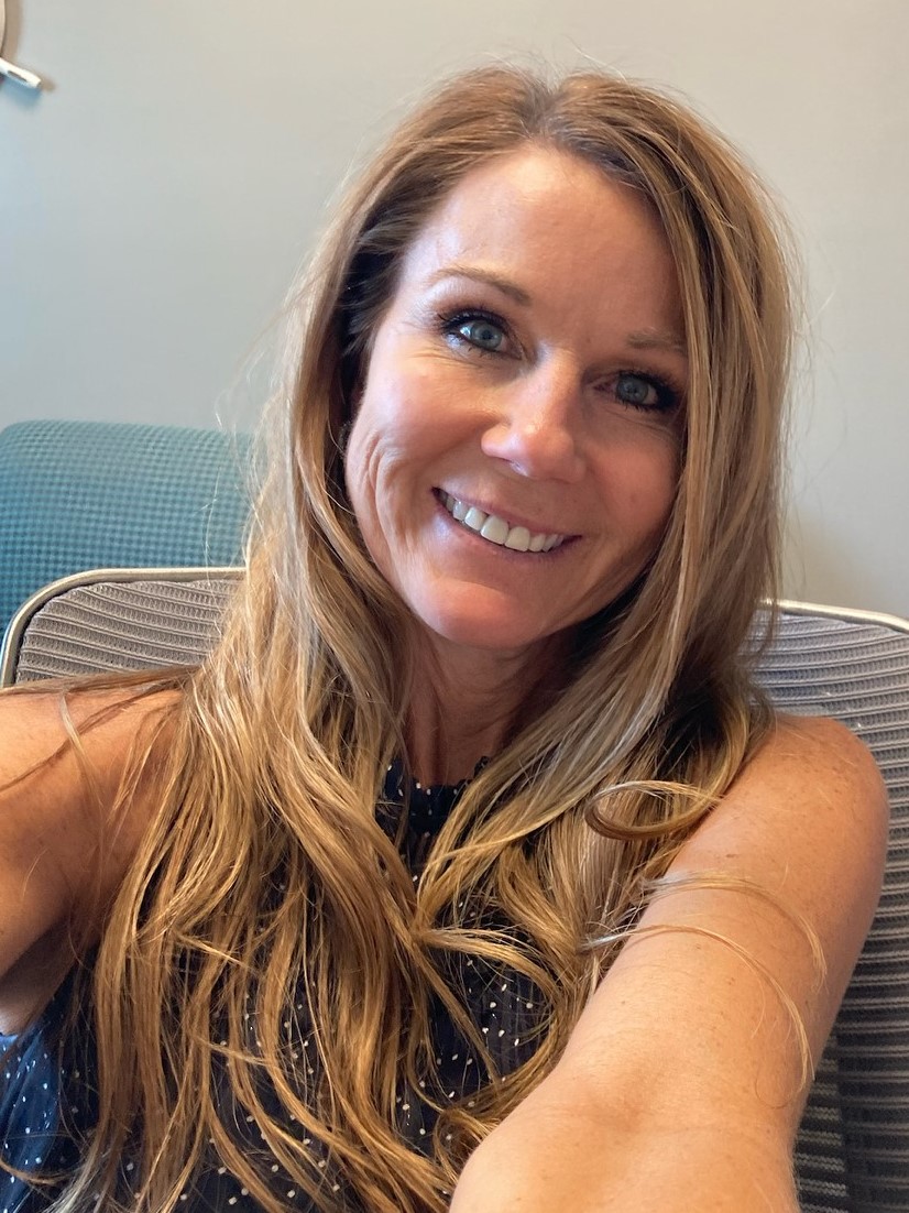 a selfie headshot of a white woman with long hair smiling at the camera