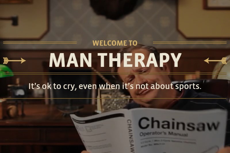 A screenshot of a website. A middle aged moustachioed white man reads a chainsaw manual with the words "Welcome to Man Therapy: It's ok to cry, even when it's not about sports" superimposed over the image.